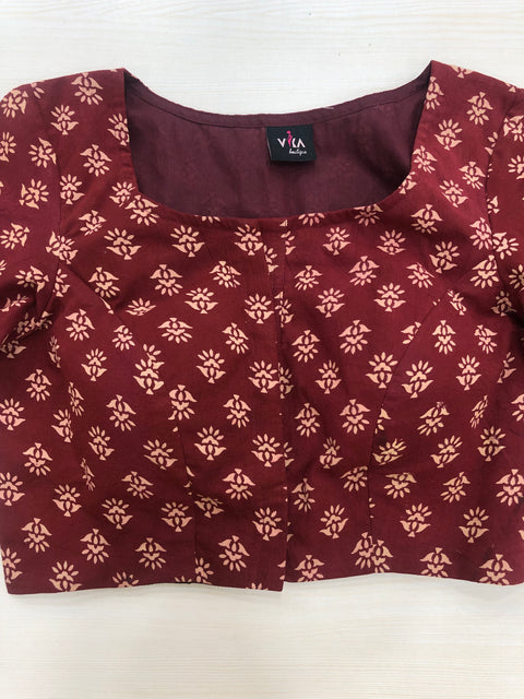 A multicolored cotton blouse by VIKA Boutique is displayed flat on a light surface. This blouse features a vibrant floral pattern, a square neckline, and 3/4 sleeves.